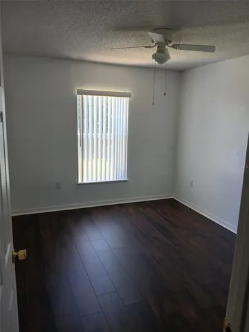 an empty room with wooden floor ceiling fan and windows