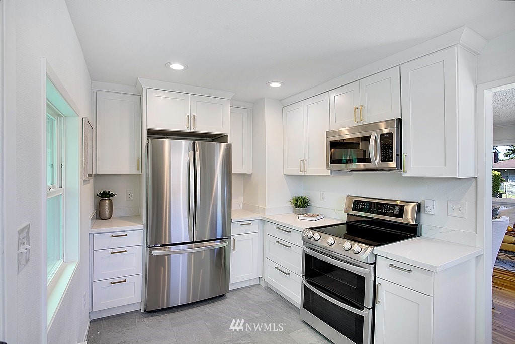 9226 13th Avenue Southwest Seattle, WA 98106 - Photo 5 of 13 a kitchen with stainless steel appliances white cabinets and a refrigerator