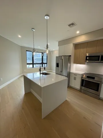 a large kitchen with stainless steel appliances a large counter top a stove a sink and a refrigerator