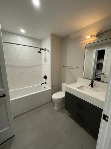 a bathroom with a bathtub sink mirror vanity and toilet