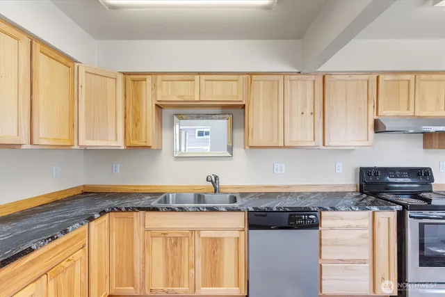 a kitchen with stainless steel appliances granite countertop a stove a sink and a white cabinets
