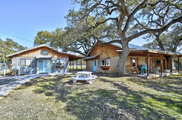 a wooden house with large trees and outdoor space