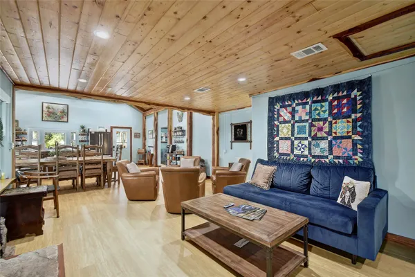 a living room with furniture a rug kitchen view and a large window