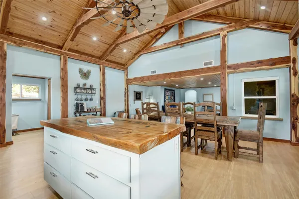 a view of dining room with kitchen island stainless steel appliances wooden floor dining table and chairs
