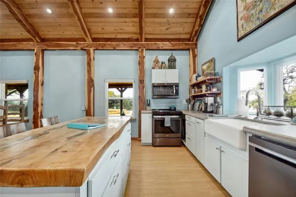 a large kitchen with granite countertop a sink and dishwasher a stove top oven with wooden floor