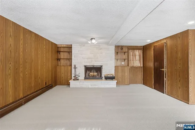 a view of an empty room with wooden floor and a fireplace