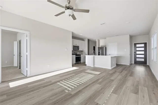 a view of a living room with wooden floor and kitchen view