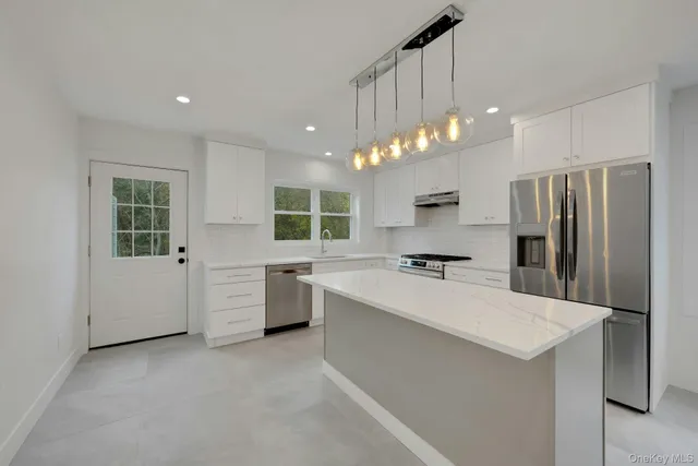 a large kitchen with kitchen island a sink stainless steel appliances and cabinets