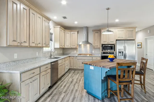 a kitchen with stainless steel appliances granite countertop a white cabinets wooden floor and a refrigerator