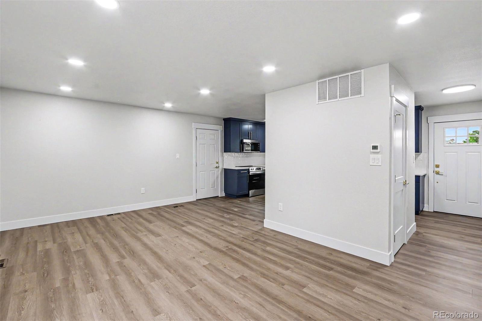 809 Gallup Road Fort Collins, CO 80521 - Photo 9 of 20 a view of an empty room with wooden floor and a kitchen