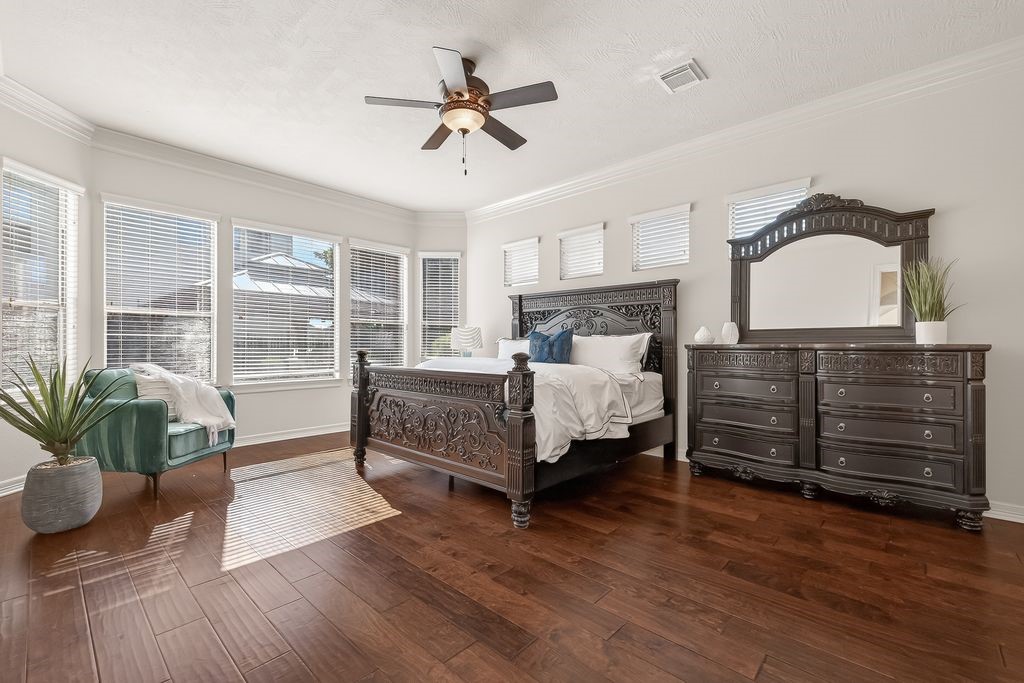 8115 Salta Verde Point Katy, TX 77494 - Photo 6 of 50 a bedroom with a bed a chandelier and potted plants on the dresser