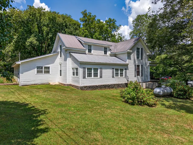 a view of a swimming pool with a yard and large trees