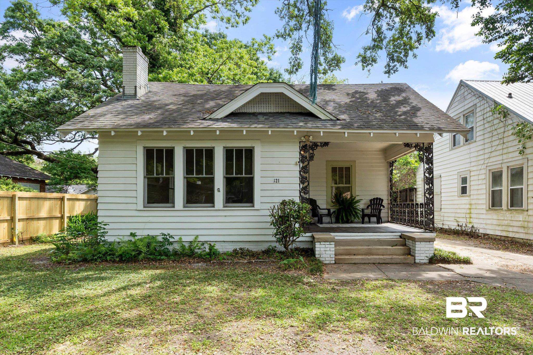 Back of property with a chimney, a lawn, a shingled roof, fence, and a porch