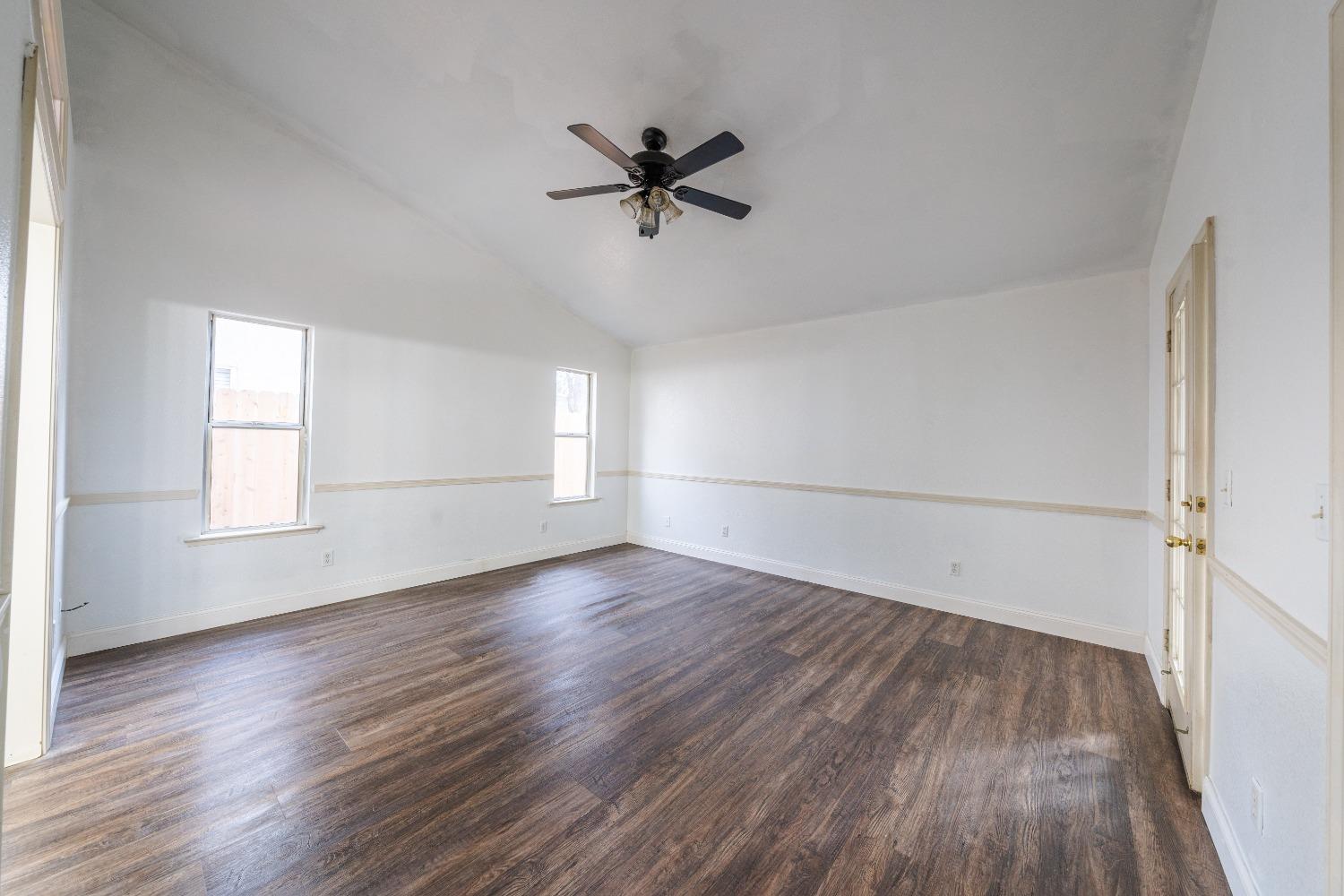 118 Oak Avenue Clovis, CA 93611 - Photo 16 of 22 an empty room with wooden floor a ceiling fan and windows