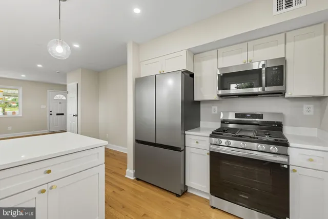 a kitchen with stainless steel appliances white cabinets and a stove top oven