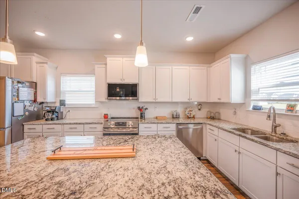 a living room with furniture kitchen area and a wooden floor