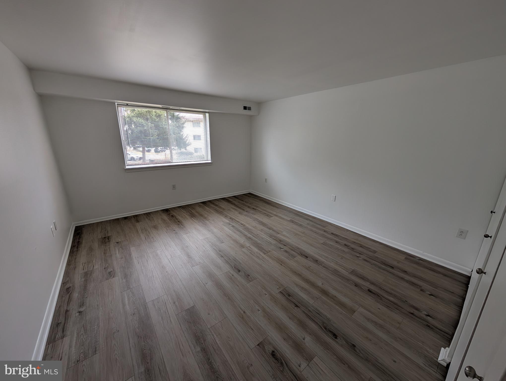 11402 Cherry Hill Road, Unit 103 Beltsville, MD 20705 - Photo 12 of 26 a view of an empty room with wooden floor and a window