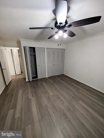 a view of an empty room with wooden floor and a ceiling fan