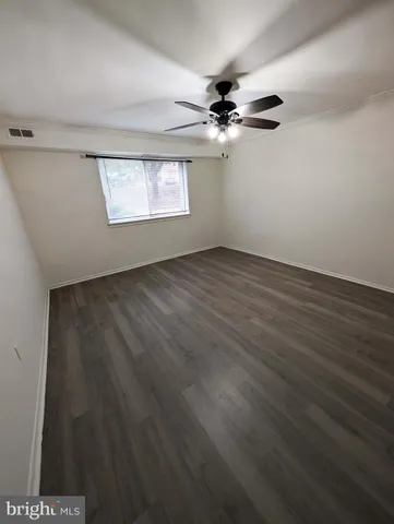 an empty room with wooden floor ceiling fan and windows