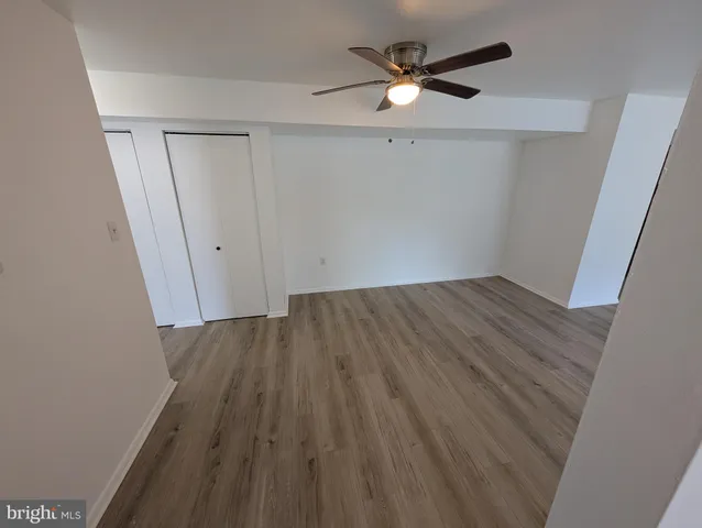 an empty room with wooden floor fan and windows