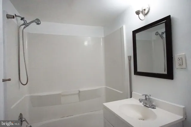 a bathroom with a granite countertop sink a mirror and shower
