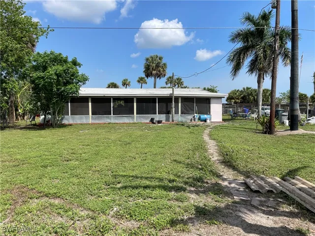 a view of a house with a yard and palm trees