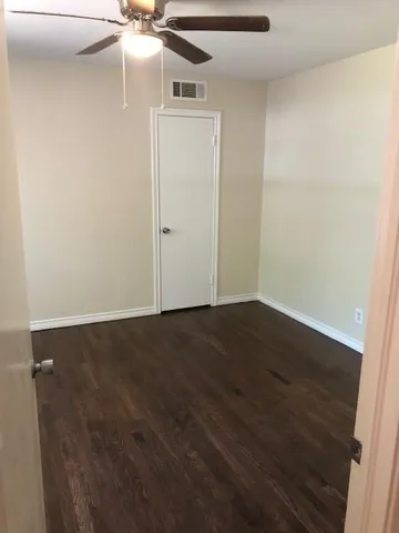 an empty room with wooden floor and fan