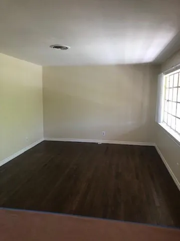 en empty room with wooden floor and windows