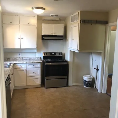 a kitchen with stainless steel appliances granite countertop a stove a refrigerator and a white cabinets