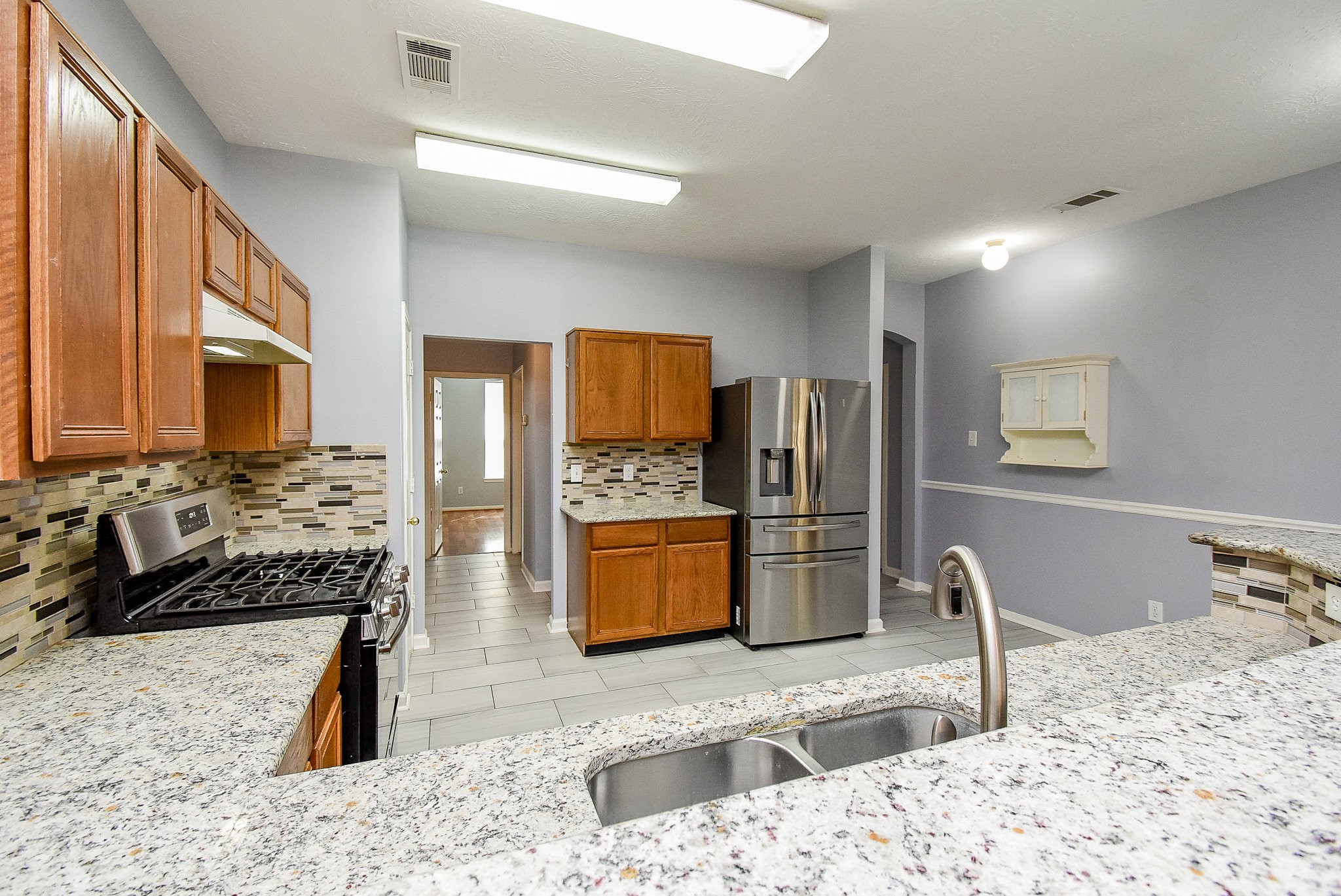 5431 Gosforth Drive Katy, TX 77449 - Photo 4 of 15 a kitchen with stainless steel appliances kitchen island granite countertop a refrigerator and a stove top oven