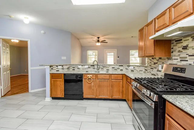 a kitchen with stainless steel appliances granite countertop a stove a sink and a refrigerator