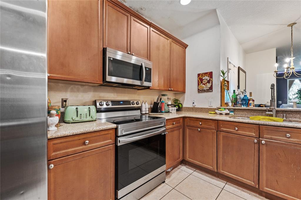 6039 Strada Isle Way Orlando, FL 32835 - Photo 4 of 24 a kitchen with stainless steel appliances granite countertop a sink and a stove top oven