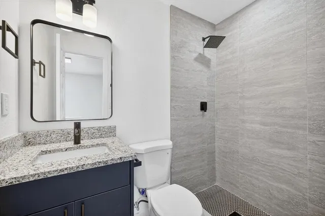 a bathroom with a granite countertop sink toilet a mirror and shower