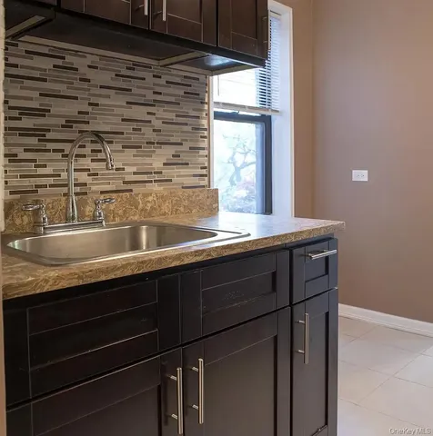 a sink with granite countertop cabinets and window