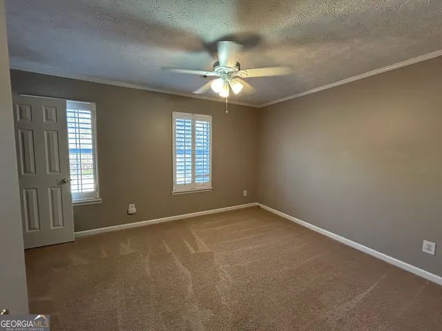 an empty room with windows and fan