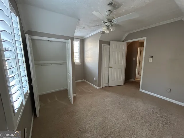 an empty room with windows and fan