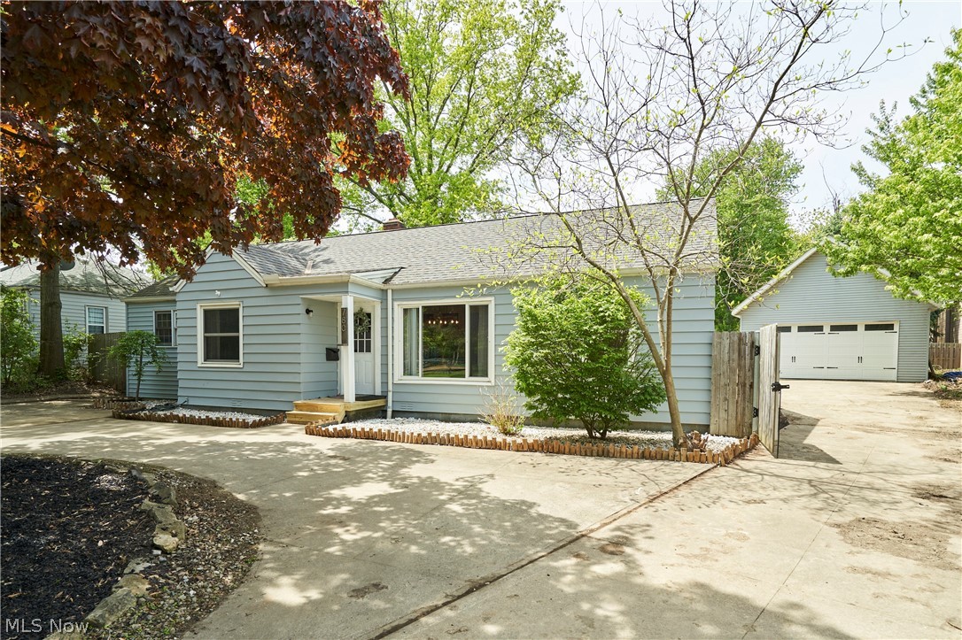 Light blue siding exterior featuring a covered entry, established landscaping, and an attached two-car garage