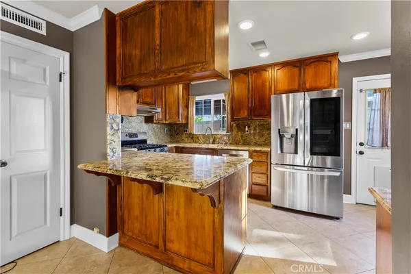 a kitchen with stainless steel appliances granite countertop wooden cabinets a stove and a refrigerator