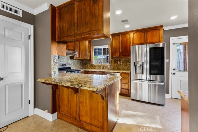 a kitchen with stainless steel appliances granite countertop wooden cabinets a stove and a refrigerator
