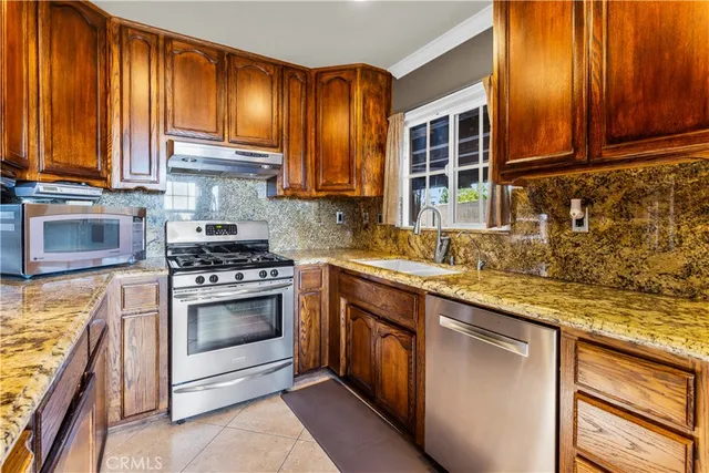 a kitchen with stainless steel appliances granite countertop a stove a sink and a microwave