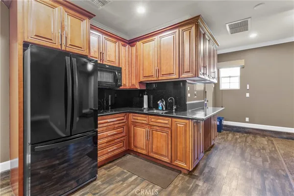 a kitchen with stainless steel appliances granite countertop a refrigerator a sink dishwasher and wooden cabinets with wooden floor