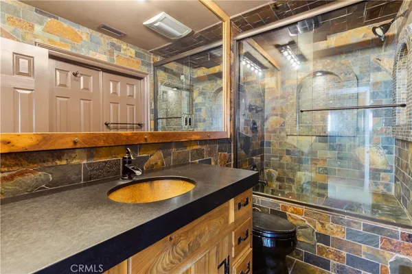 a bathroom with a granite countertop sink a mirror and a shower