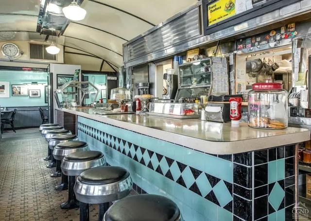 a room with stainless steel appliances kitchen island granite countertop lots of wooden furniture and a large window