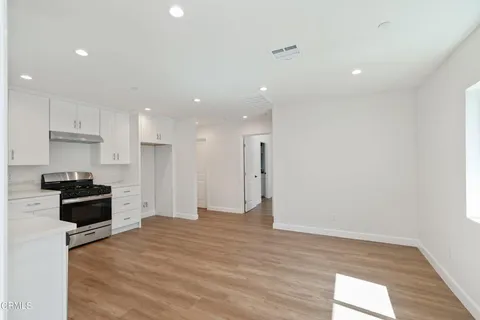 a kitchen with stainless steel appliances kitchen island granite countertop a stove a refrigerator and a wooden floor