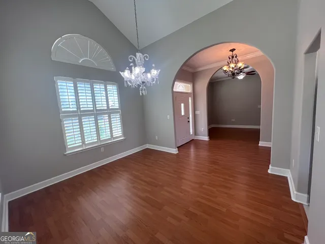 an empty room with wooden floor chandelier and window