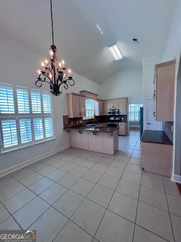a living room with granite countertop stainless steel appliances cabinets a dining table and a chandelier