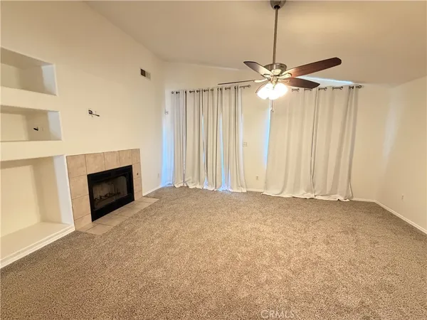 an empty room with chandelier fan and fireplace