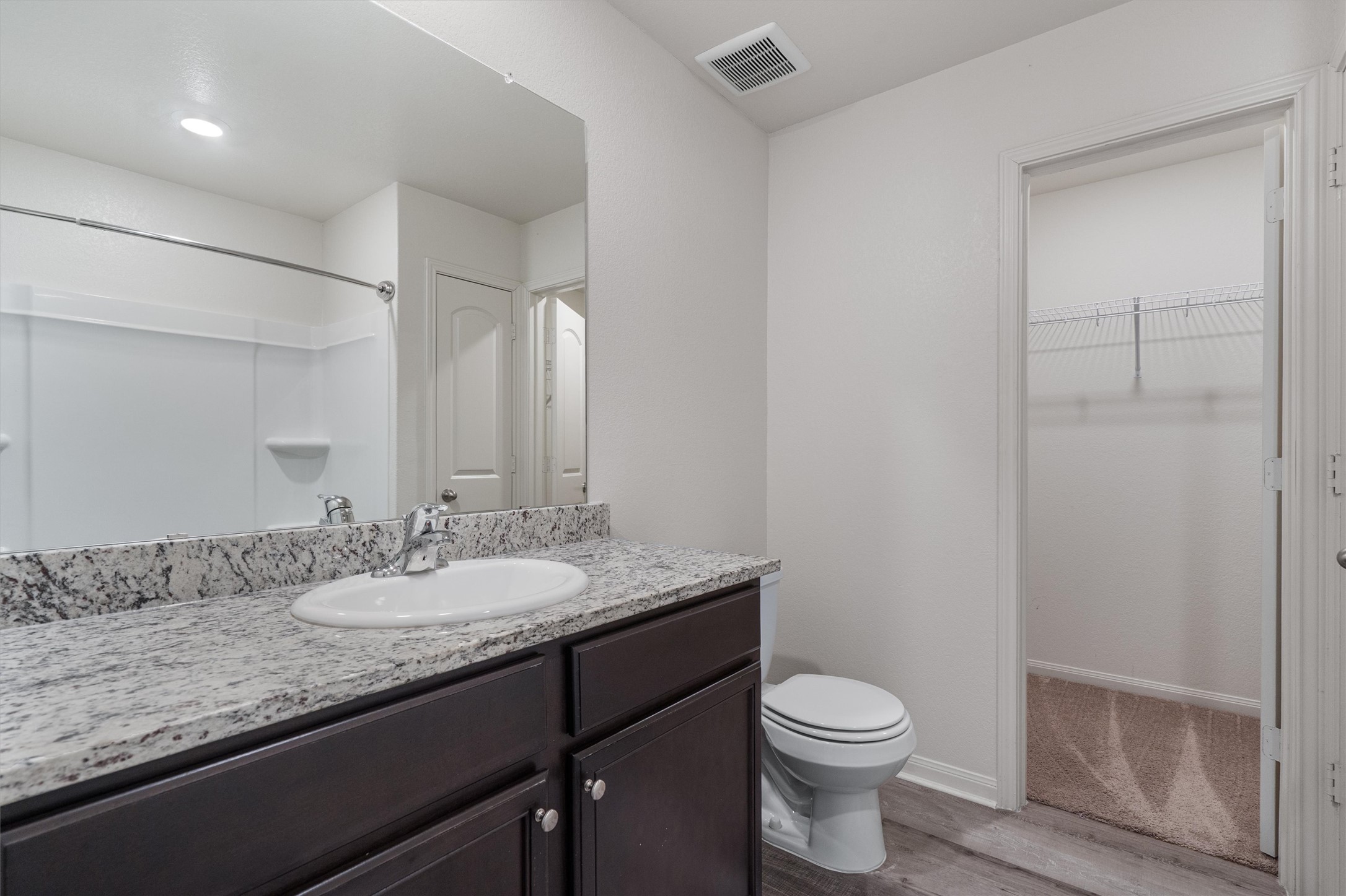 163 Niven Path, Unit 12K Jarrell, TX 76537 - Photo 18 of 39 Primary Bathroom featuring vanity, a spacious closet, light wood-style vinyl flooring, and a tub/shower combo.