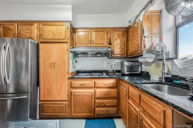 a kitchen with stainless steel appliances granite countertop a refrigerator a stove and a sink with large window