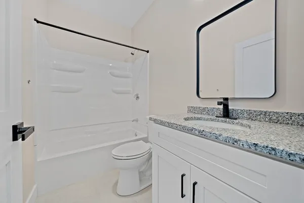 a bathroom with a granite countertop bathtub sink vanity mirror and toilet